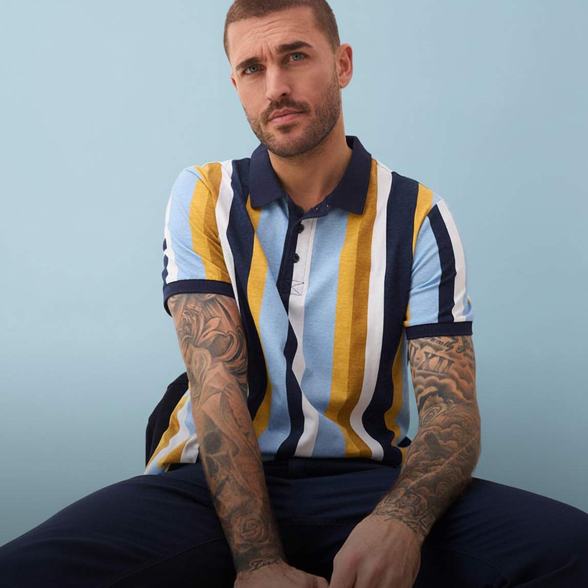 Gestreiftes Poloshirt in Blau, Gelb und Weiß, kombiniert mit einer dunkelblauen Hose.