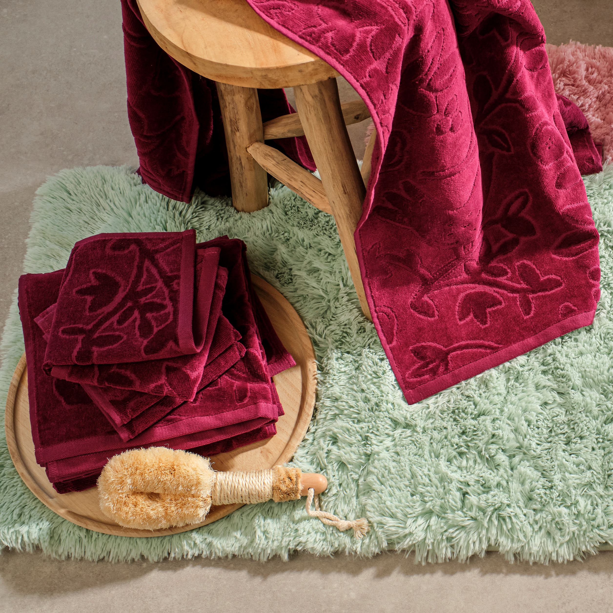 Weiche Badematte und rote Handtücher im Badezimmer.