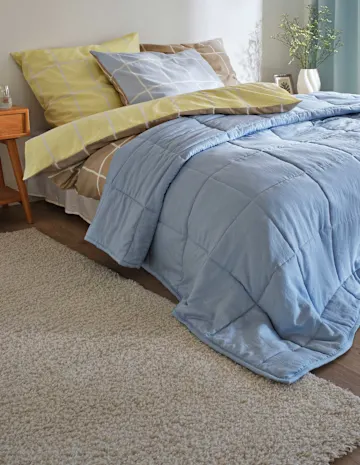 Blaue Tagedecke, gelbe und braun gemusterte Bettwäsche.