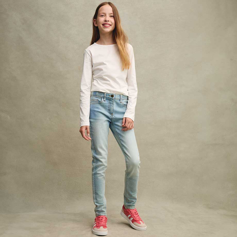 Weißer Pullover und helle Jeans kombiniert mit auffälligen roten Sneakers für einen lässigen Look.