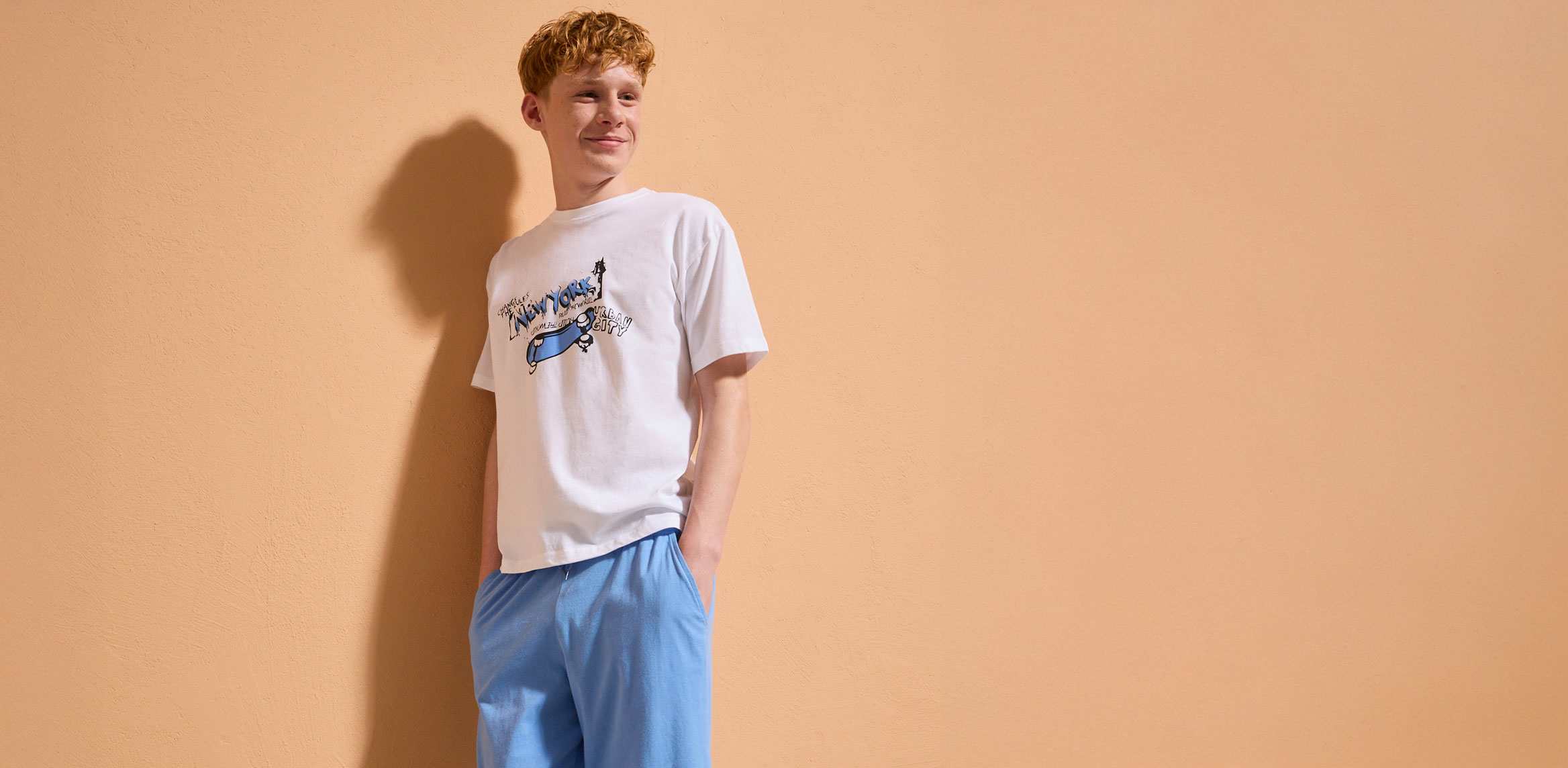 Ein Junge trägt ein weißes T-Shirt mit Print.