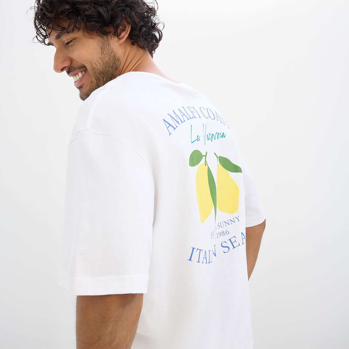 Weißes T-Shirt mit Zitronenmotiv und Schriftzug auf der Rückseite.