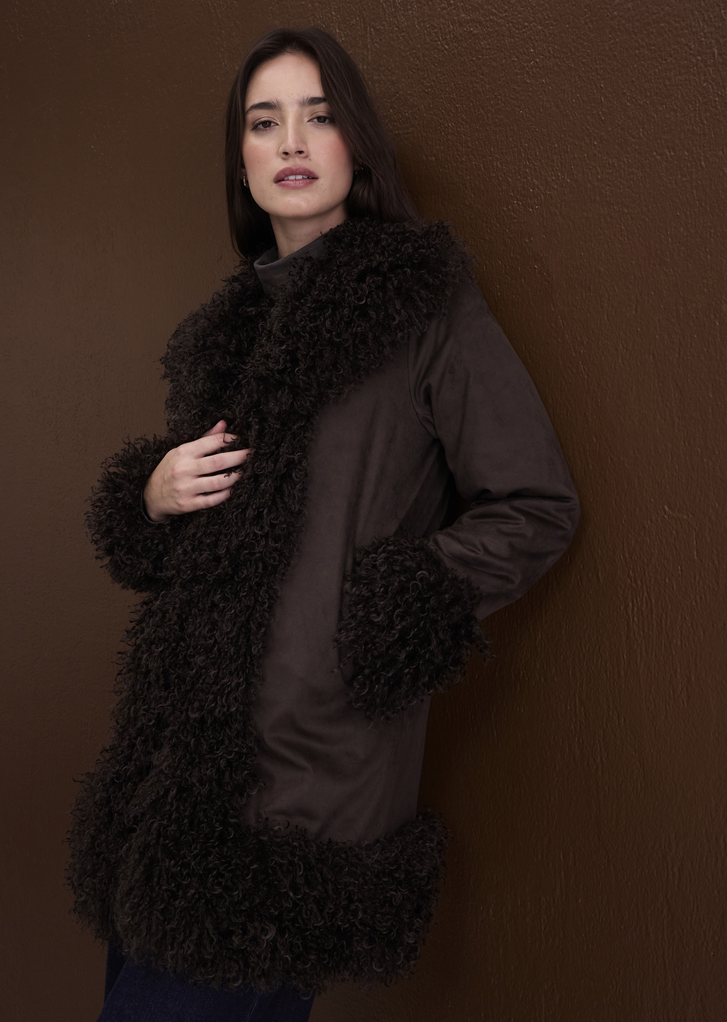 Brauner Mantel mit flauschigem Kragen und Ärmelbündchen, dazu ein Rollkragenpullover.