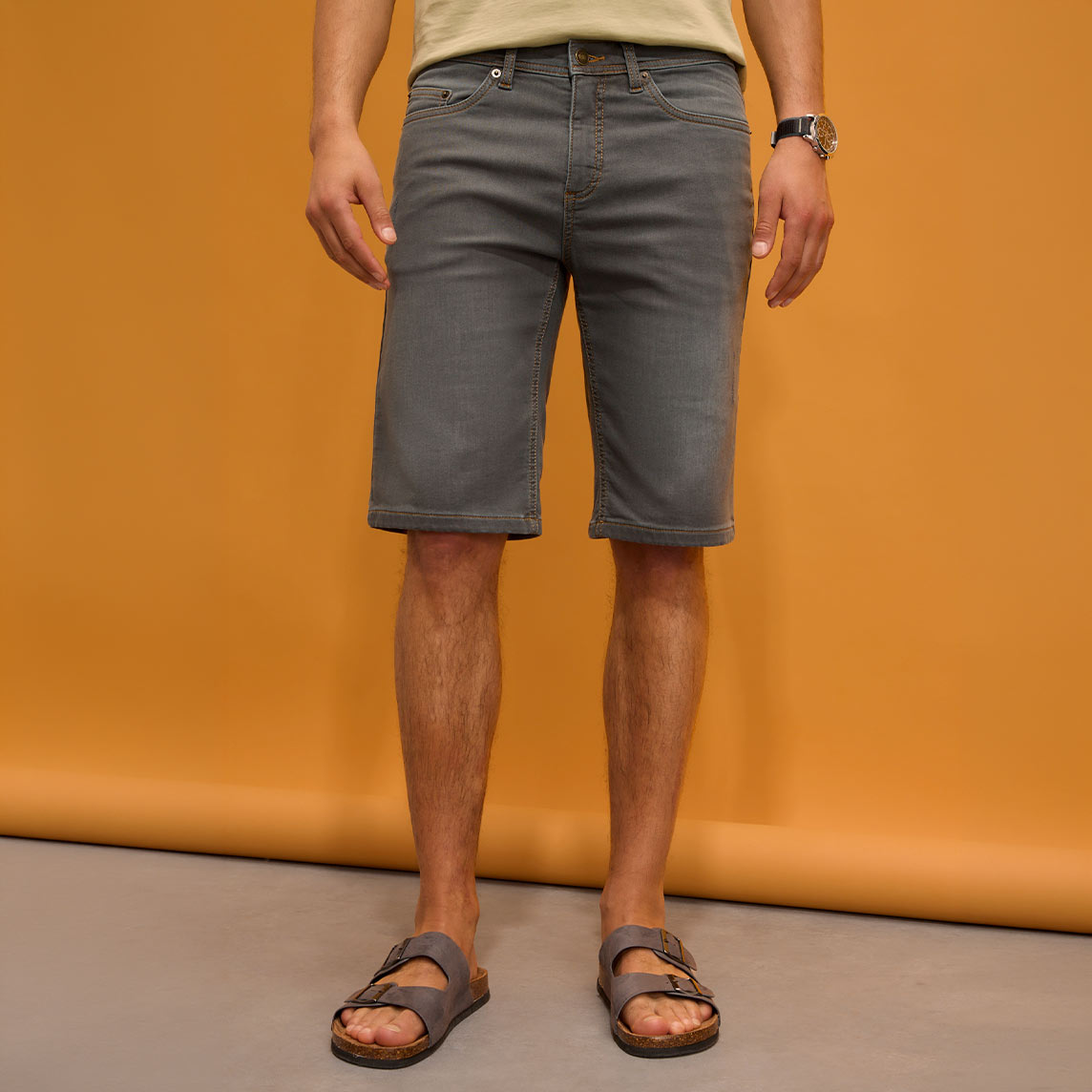 Graue Shorts, helles Shirt und bequeme Sandalen.