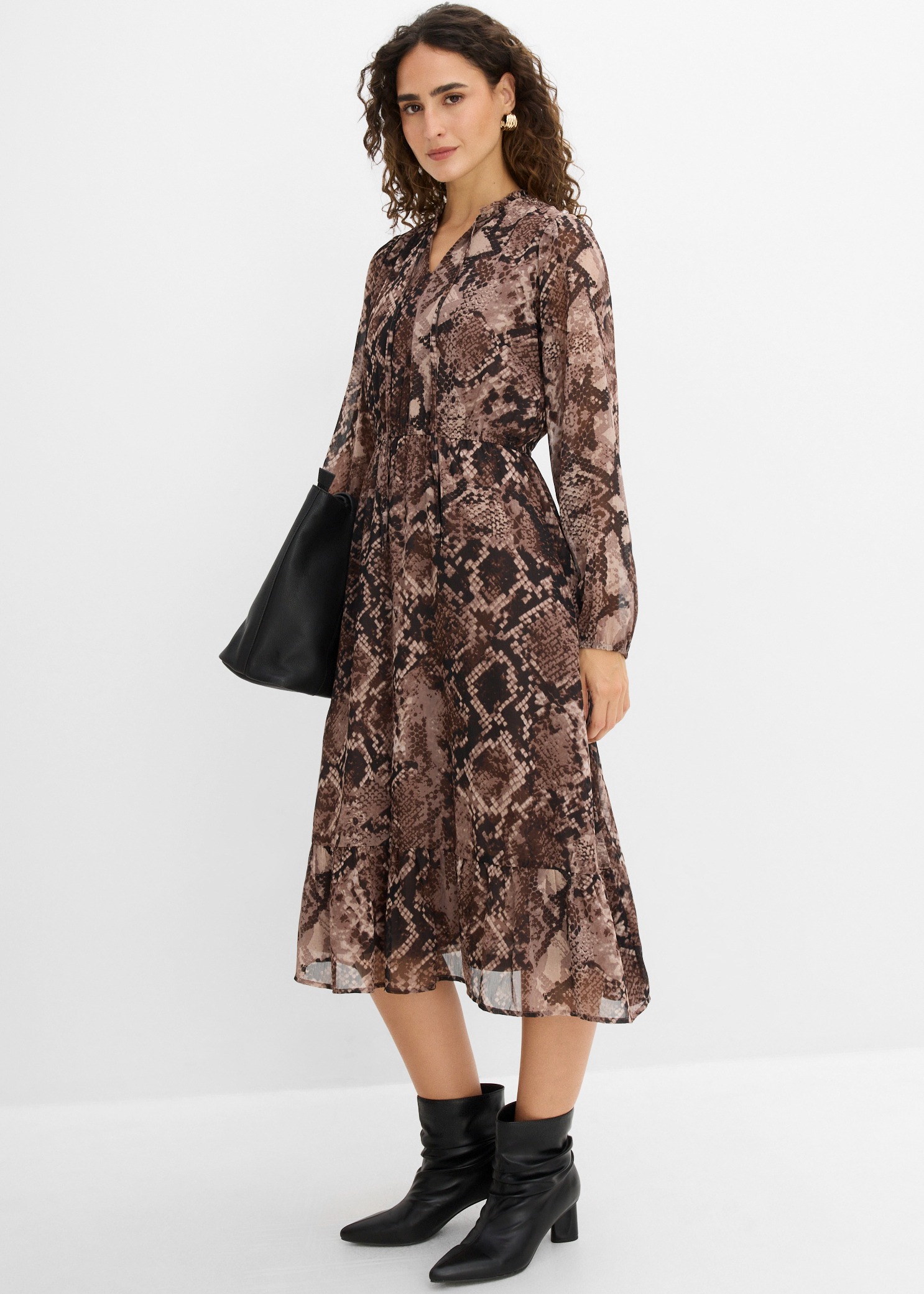 Elegantes Schlangenmuster-Kleid, schwarze Stiefeletten und Tasche.