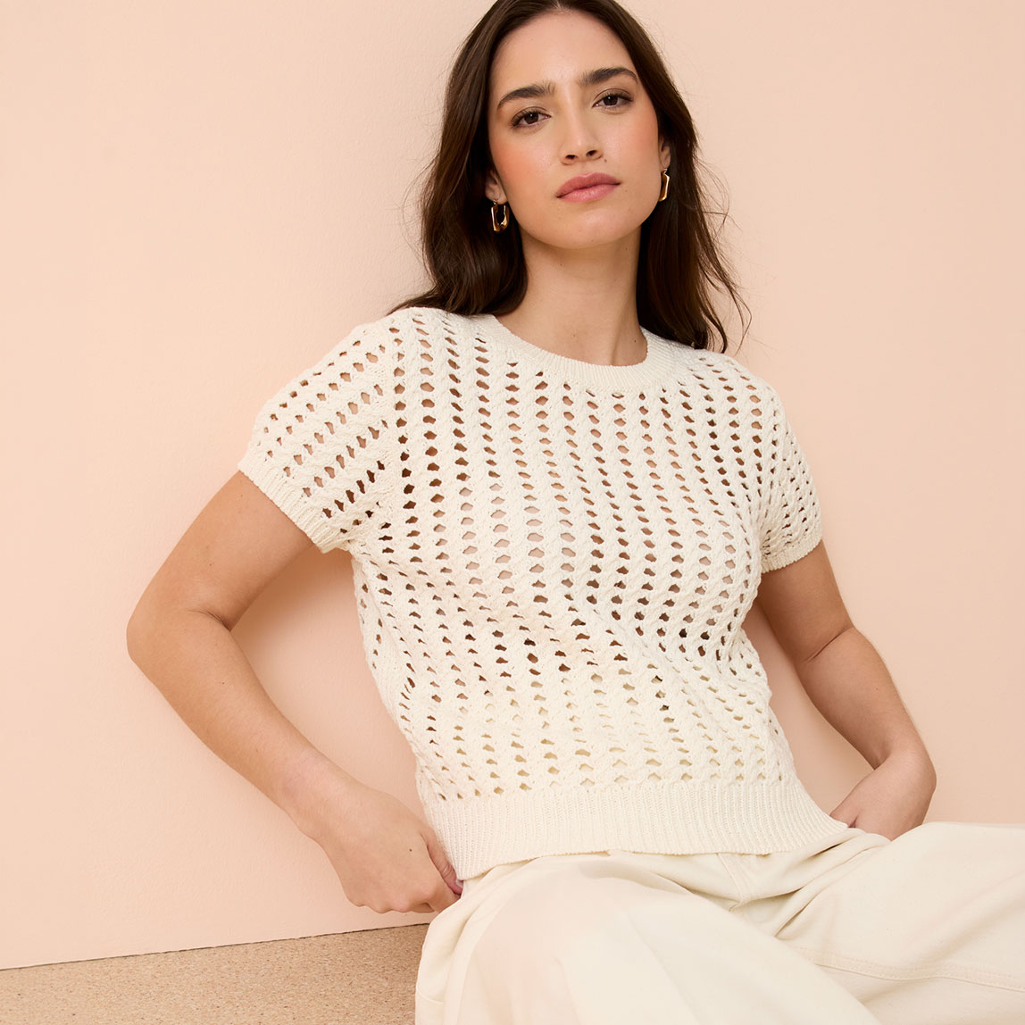 Weißer Ajour-Pullover mit kurzen Ärmeln und rundem Ausschnitt.