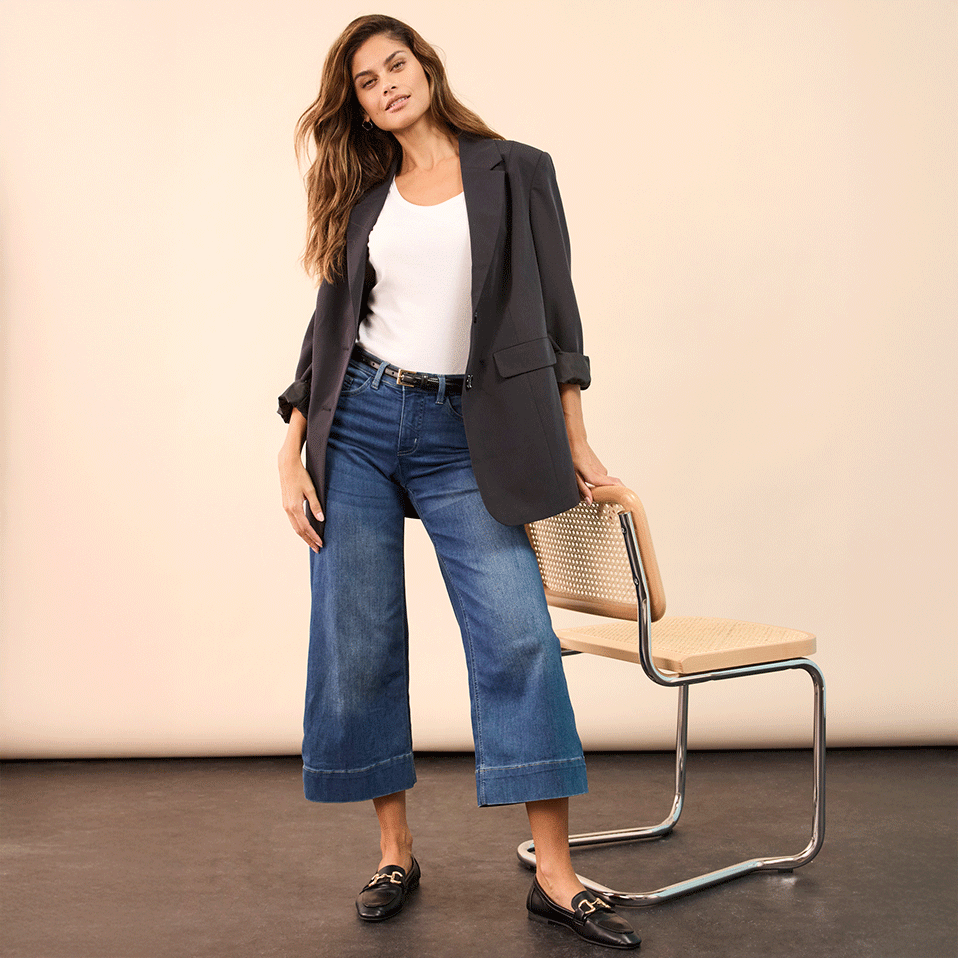 Eleganter grauer Blazer kombiniert mit weißem Top, weiten Jeans und schwarzen Loafers.