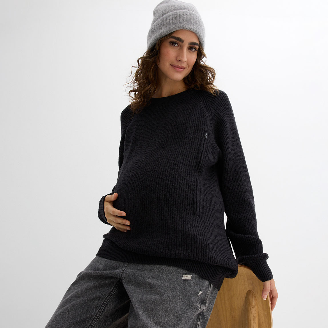 Schwarzer Umstandspullover, graue Mütze und Jeans.