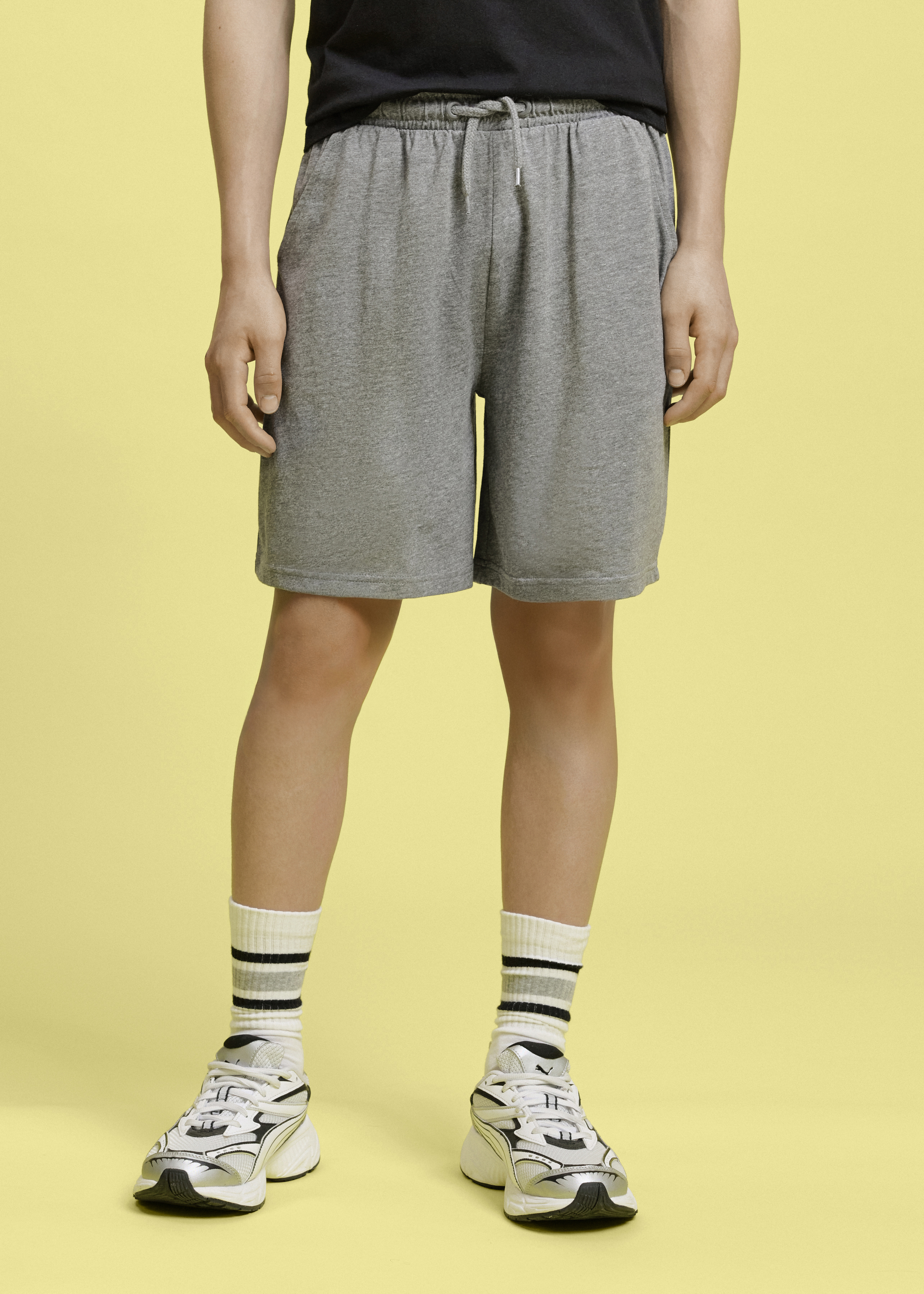 Outfit mit schwarzem Shirt und grauen Shorts.