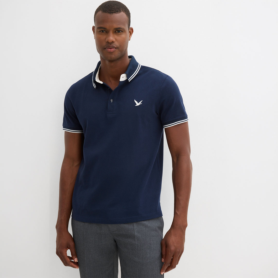Elegantes dunkelblaues Poloshirt mit weißen Kontraststreifen und grauer Hose für den modernen Mann.