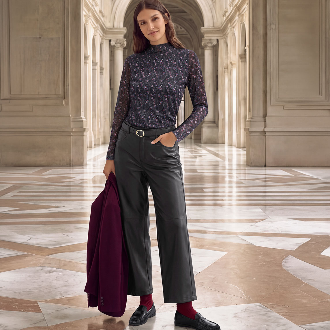 Elegantes florales Oberteil, schwarze Lederhose, rote Socken, schwarze Loafer, bordeauxfarbene Jacke.
