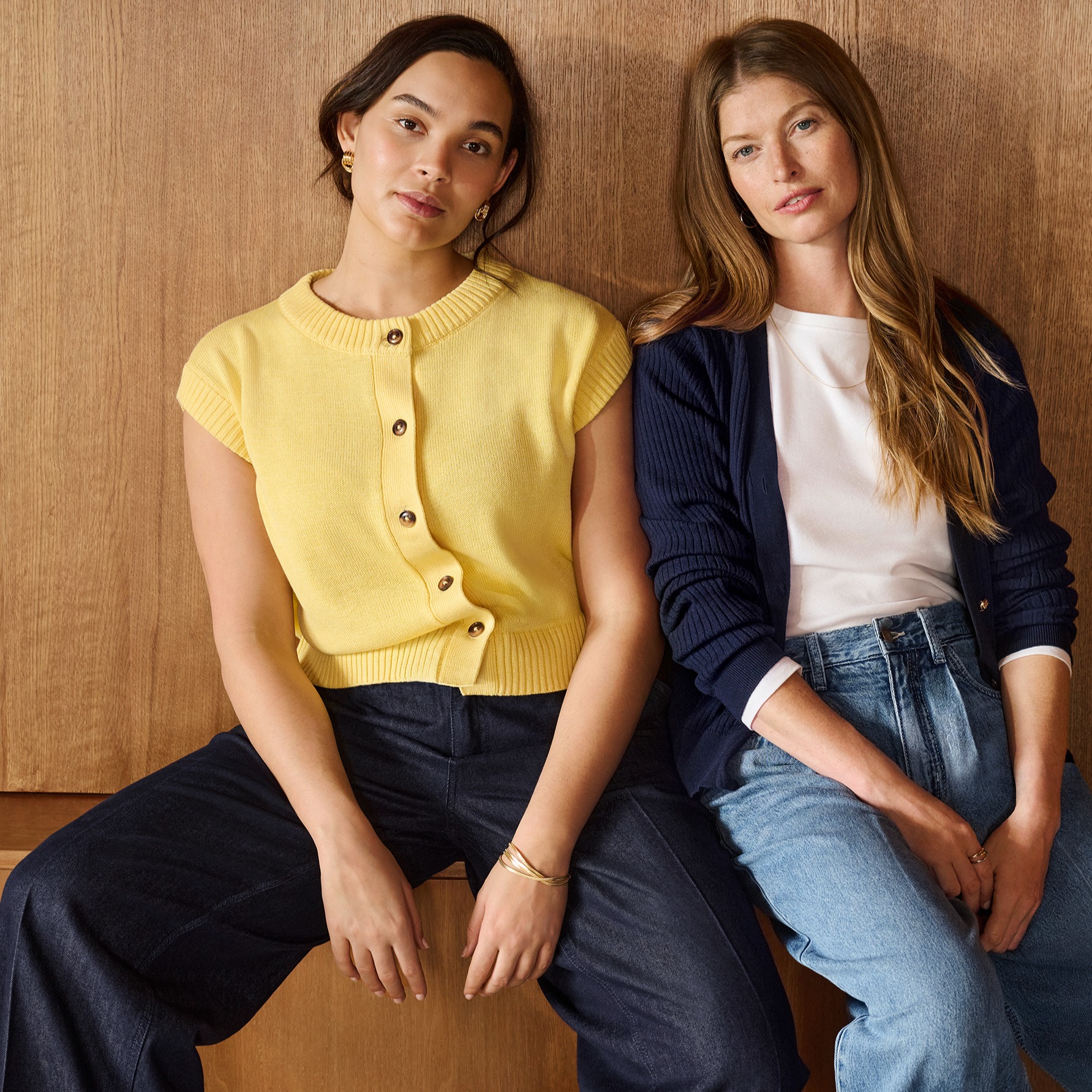 Kontrast zwischen leuchtend gelbem Kurzarm-Cardigan und marineblauer Jeans. 