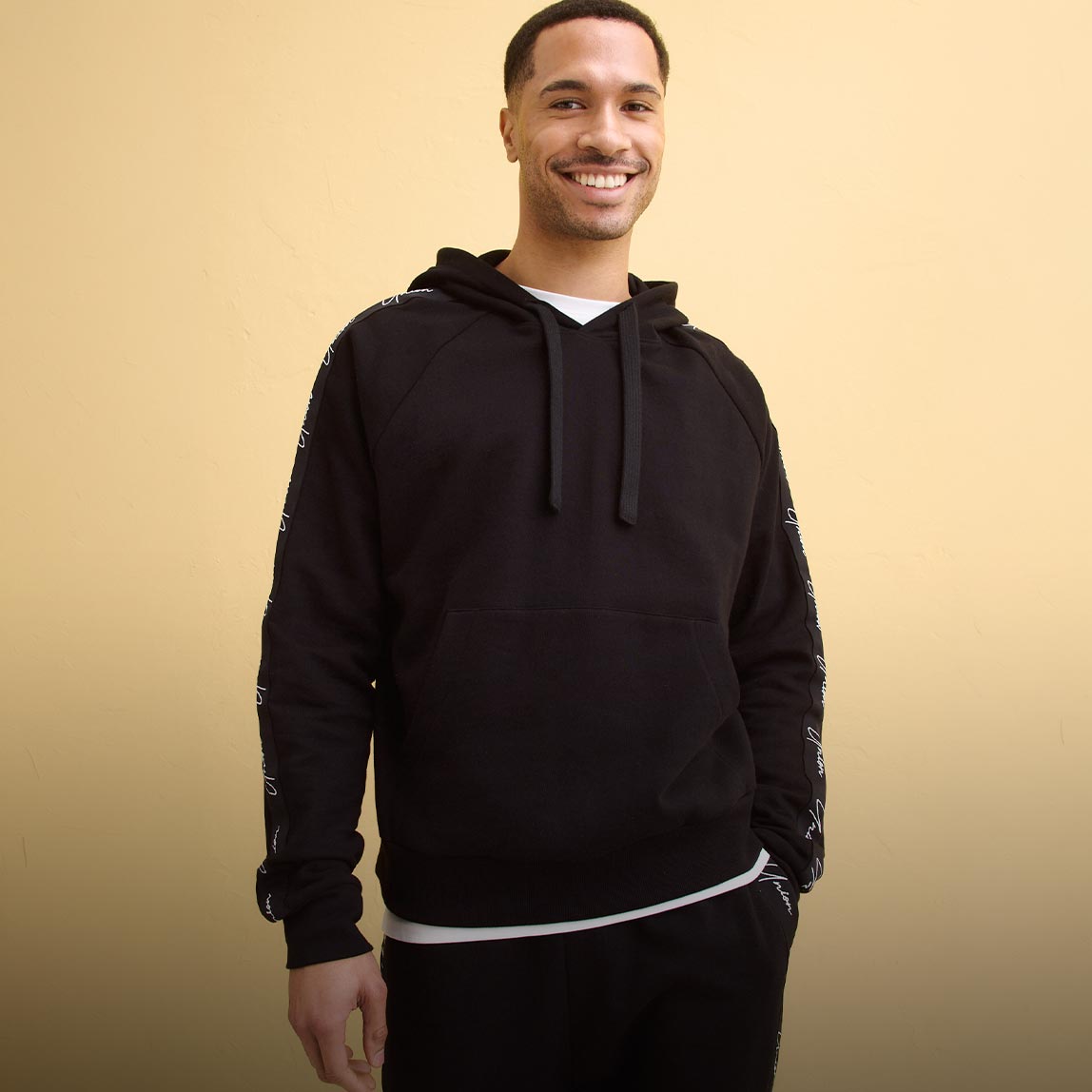 Schwarzer Kapuzenpullover über weißem T-Shirt & bequemer Hose.