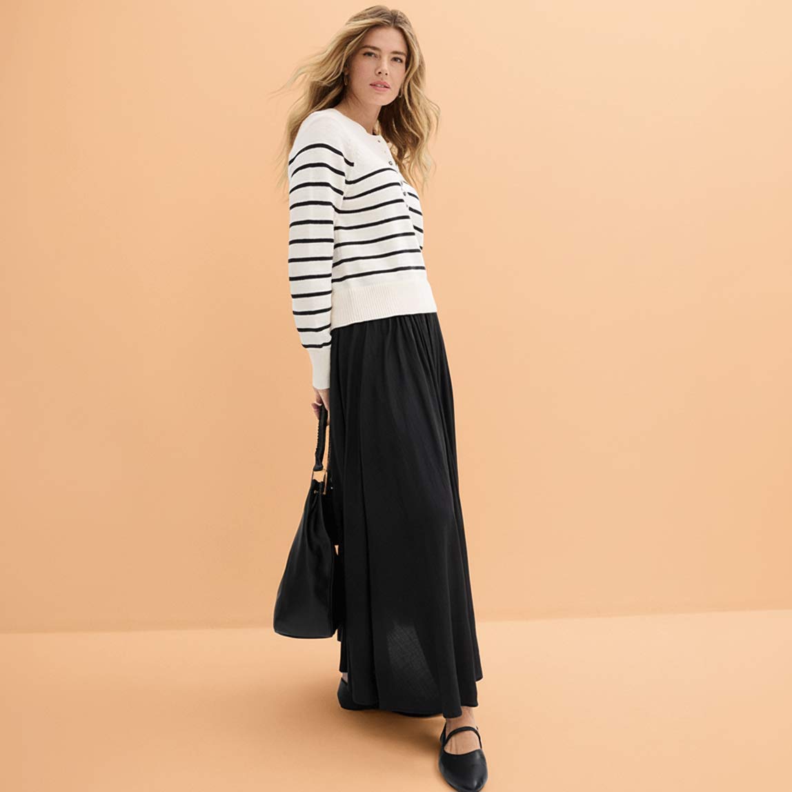 Gestreifter Pullover trifft auf langen schwarzen Rock. 