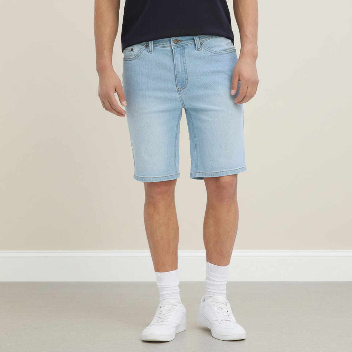 Lässige helle Jeans-Shorts, dunkles T-Shirt, weiße Socken und Sneaker.