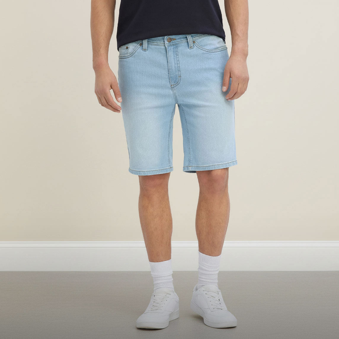 Lässige helle Jeans-Shorts, dunkles T-Shirt, weiße Socken und Sneaker.