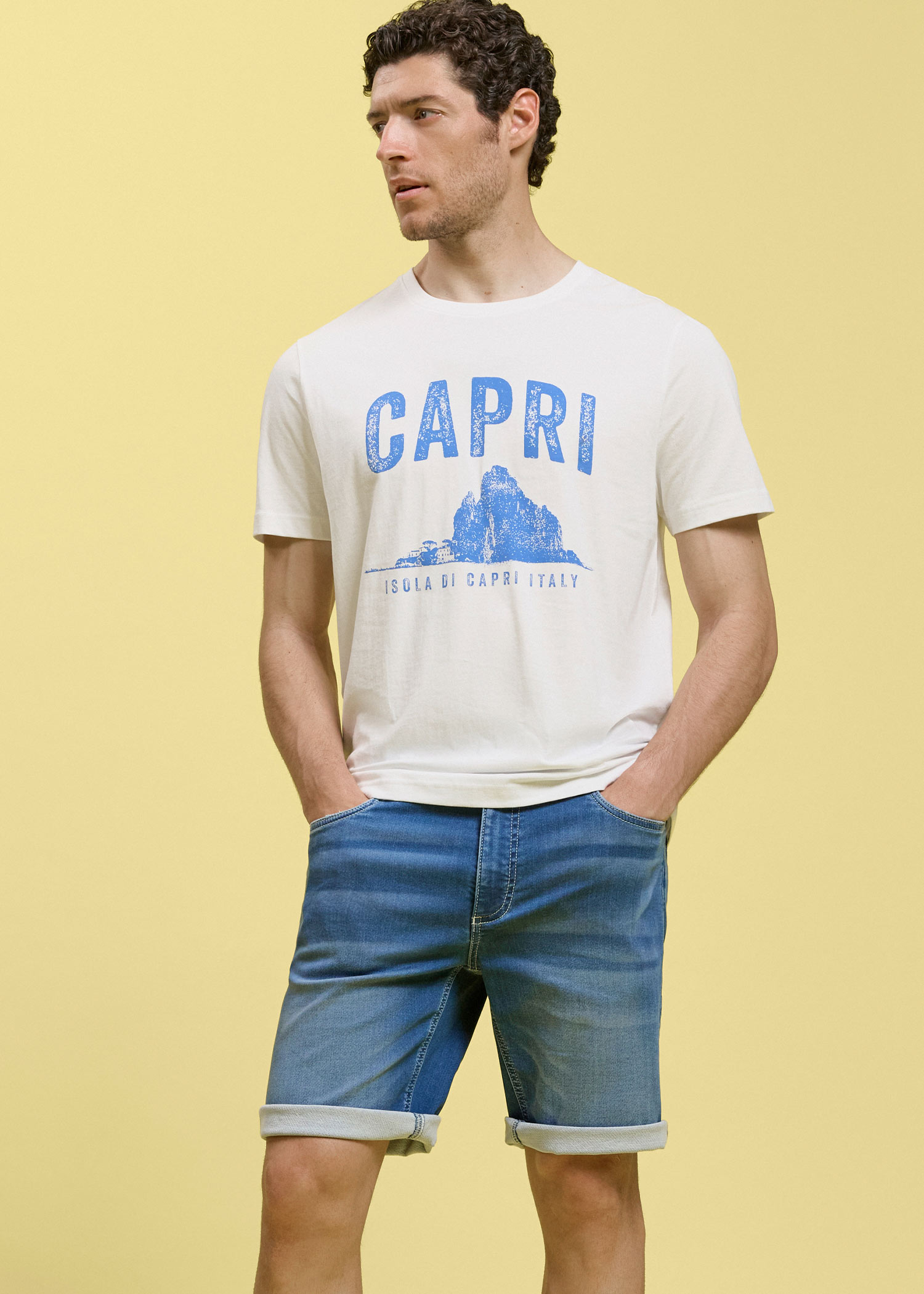 Helles T-Shirt mit Capri-Aufdruck und blaue Jeans-Shorts.