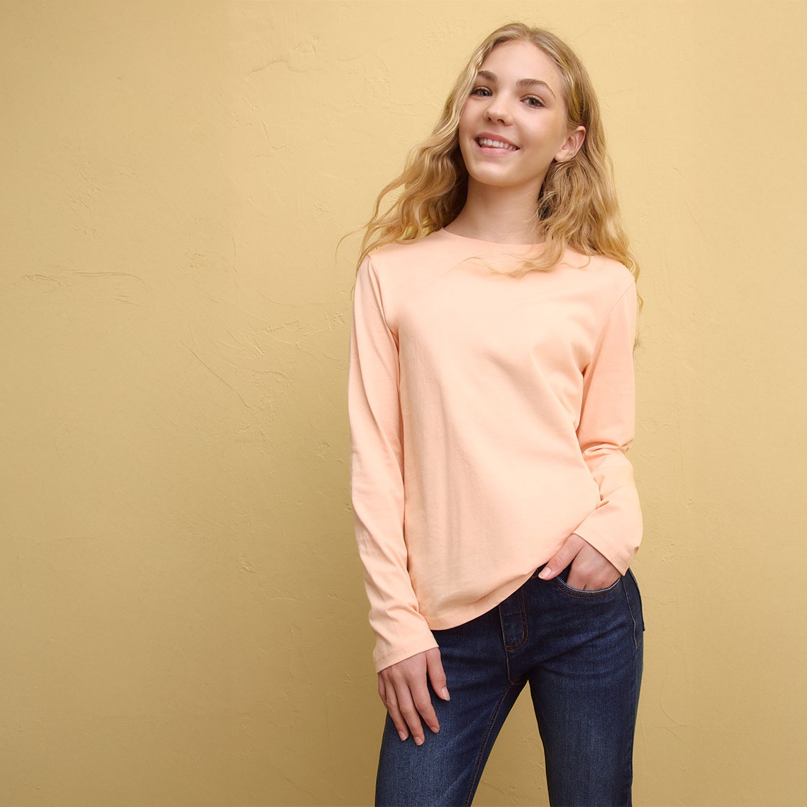 Frühlingshaftes Outfit mit apricotfarbenem Langarmshirt und dunkler Jeans. 