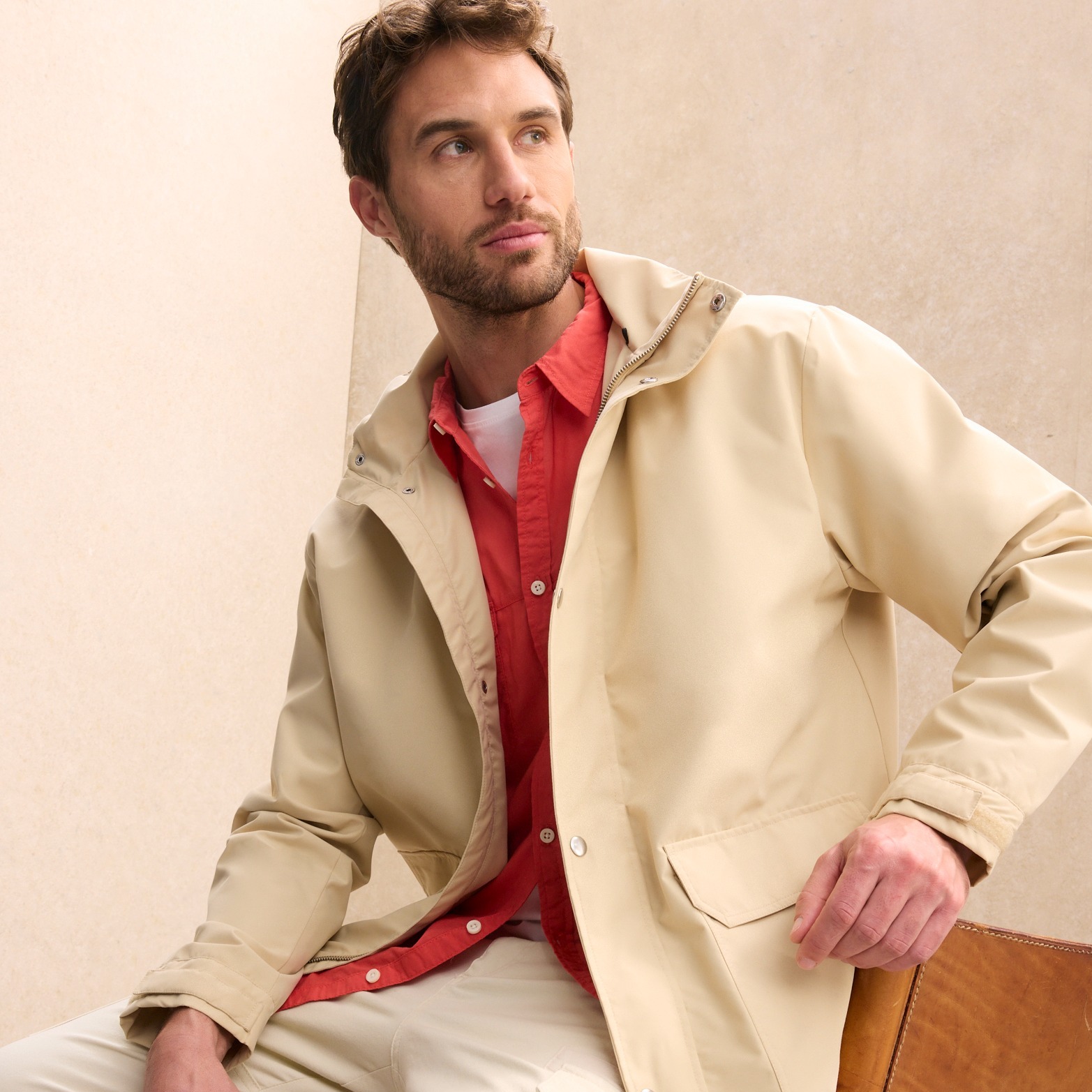 Eleganter beiger Mantel über rotem Hemd. Klassischer Stil mit modernem Touch.