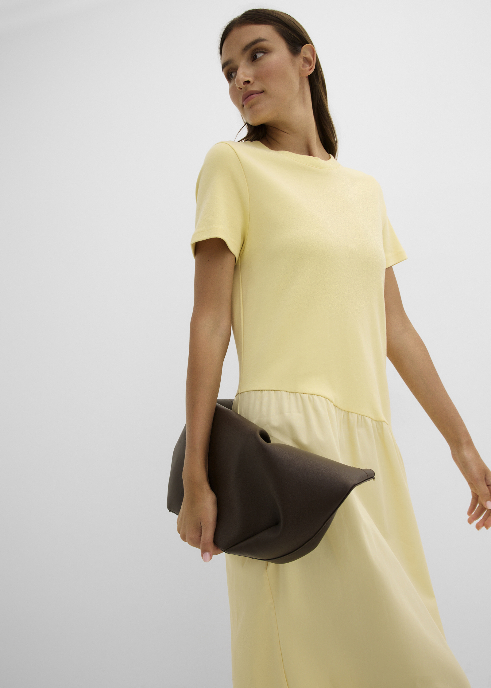 Elegantes gelbes Kleid mit kurzen Ärmeln und eine stilvolle braune Clutch.
