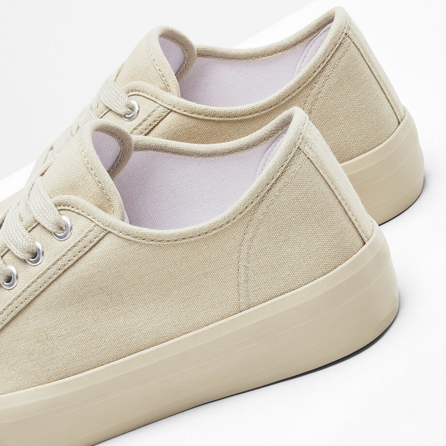 Schlichte beige Sneaker mit flacher Sohle und Schnürsenkeln. Perfekt für den lässigen Alltags-Look.