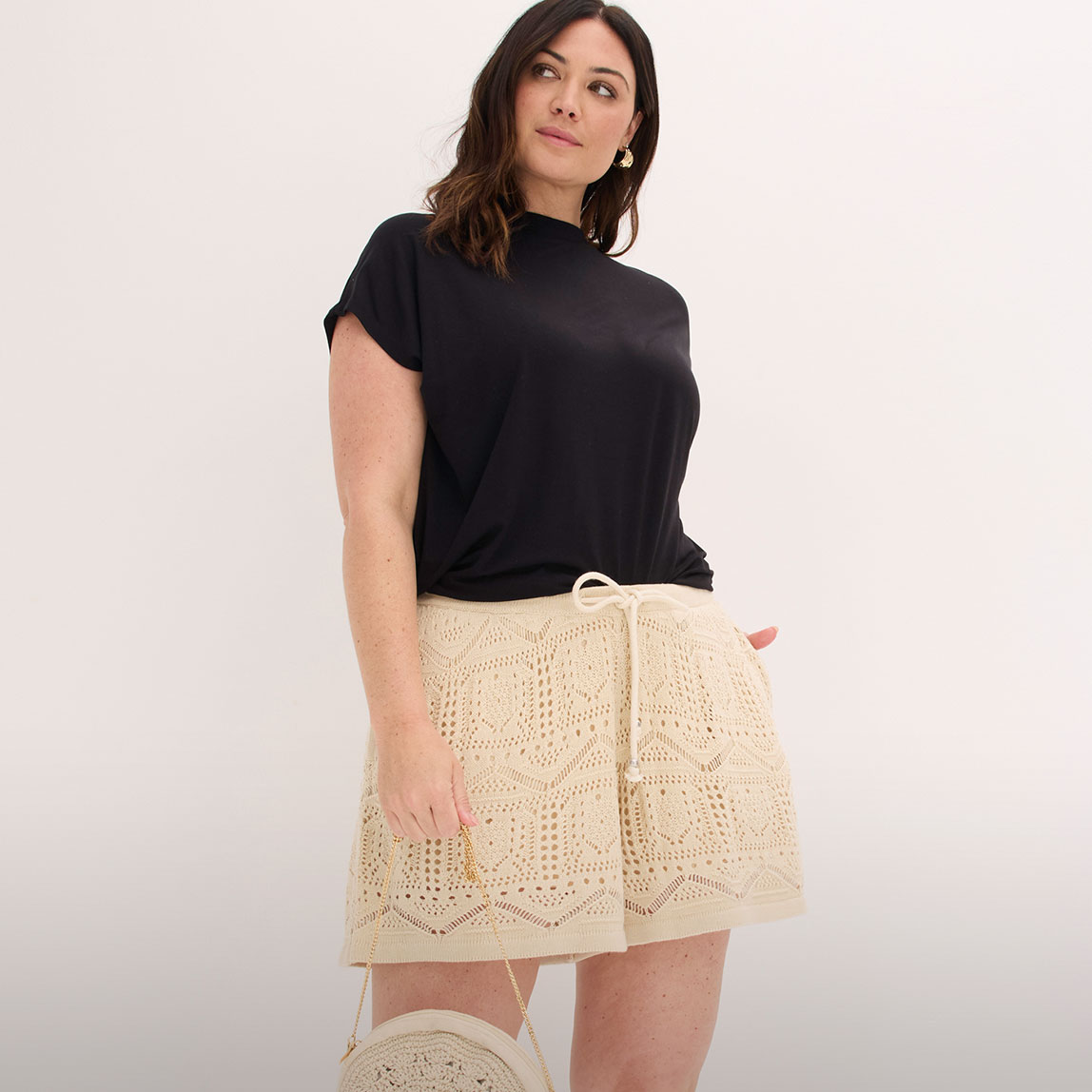 Schwarzes Oberteil und cremefarbene Häkel-Shorts mit detailreichem Muster und Kordelzug.