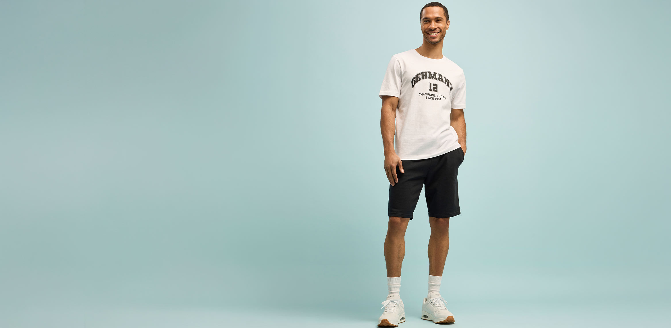Sportlicher Look mit weißem T-Shirt, schwarzen Shorts und passenden weißen Sneakers.
