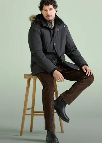 Winterlich gekleidet mit warmem Parka, brauner Cordhose und schwarzen Lederstiefeln.