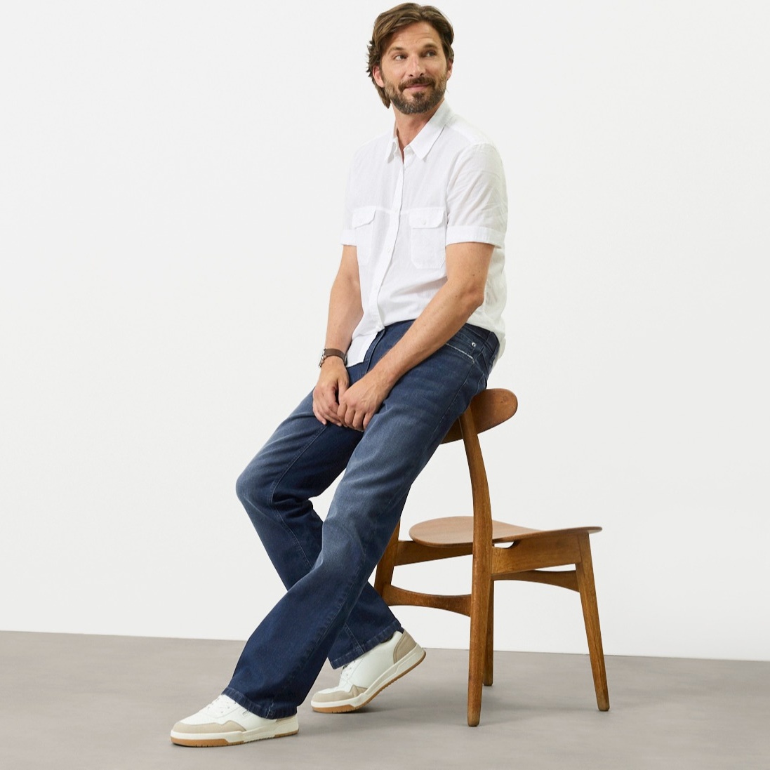 Weißes Kurzarmhemd, blaue Regular-Fit Jeans und moderne weiße Sneaker.