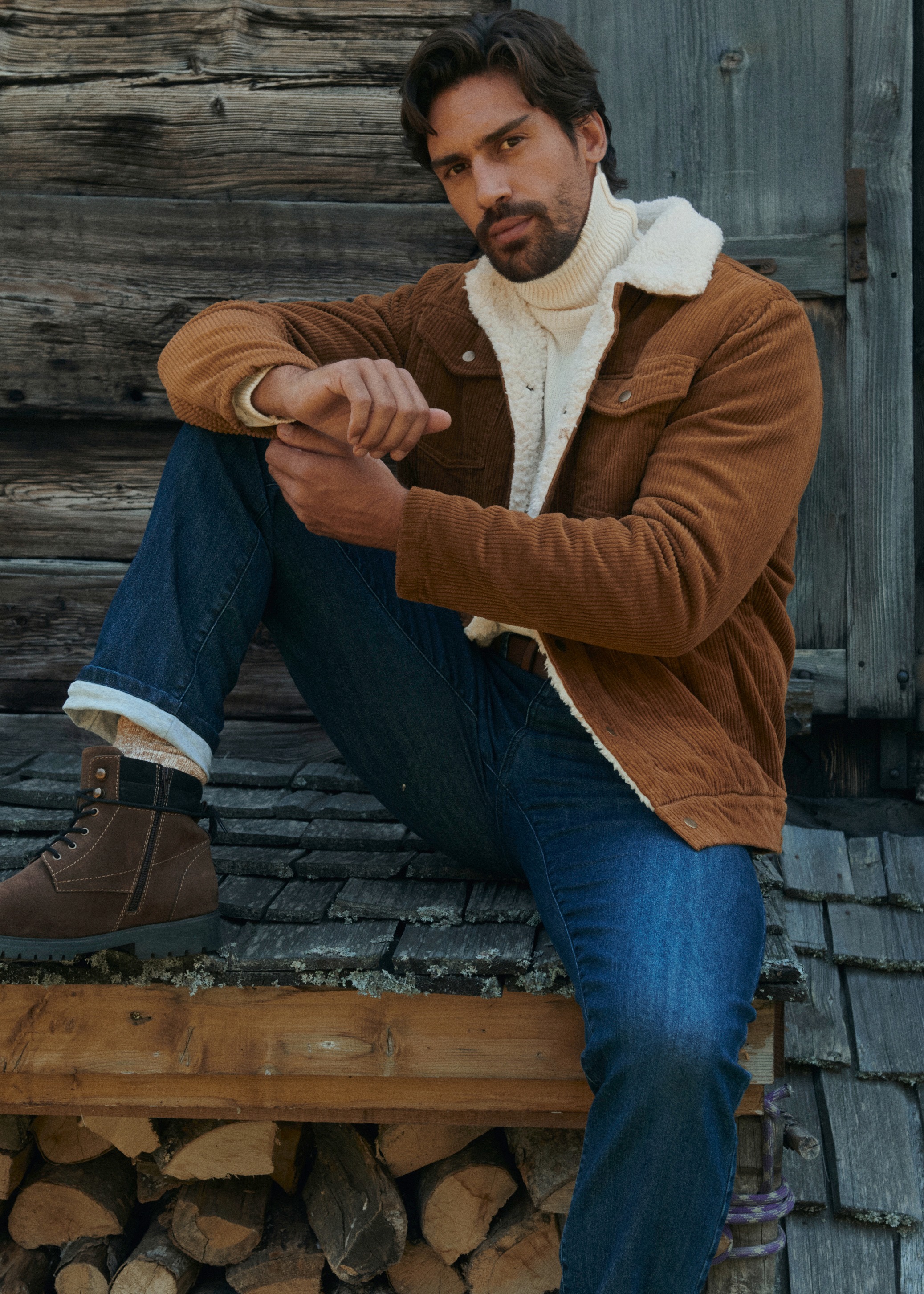 Braune Cordjacke, weißer Rollkragenpullover, Jeans und gefütterte Boots prägen das Outfit.