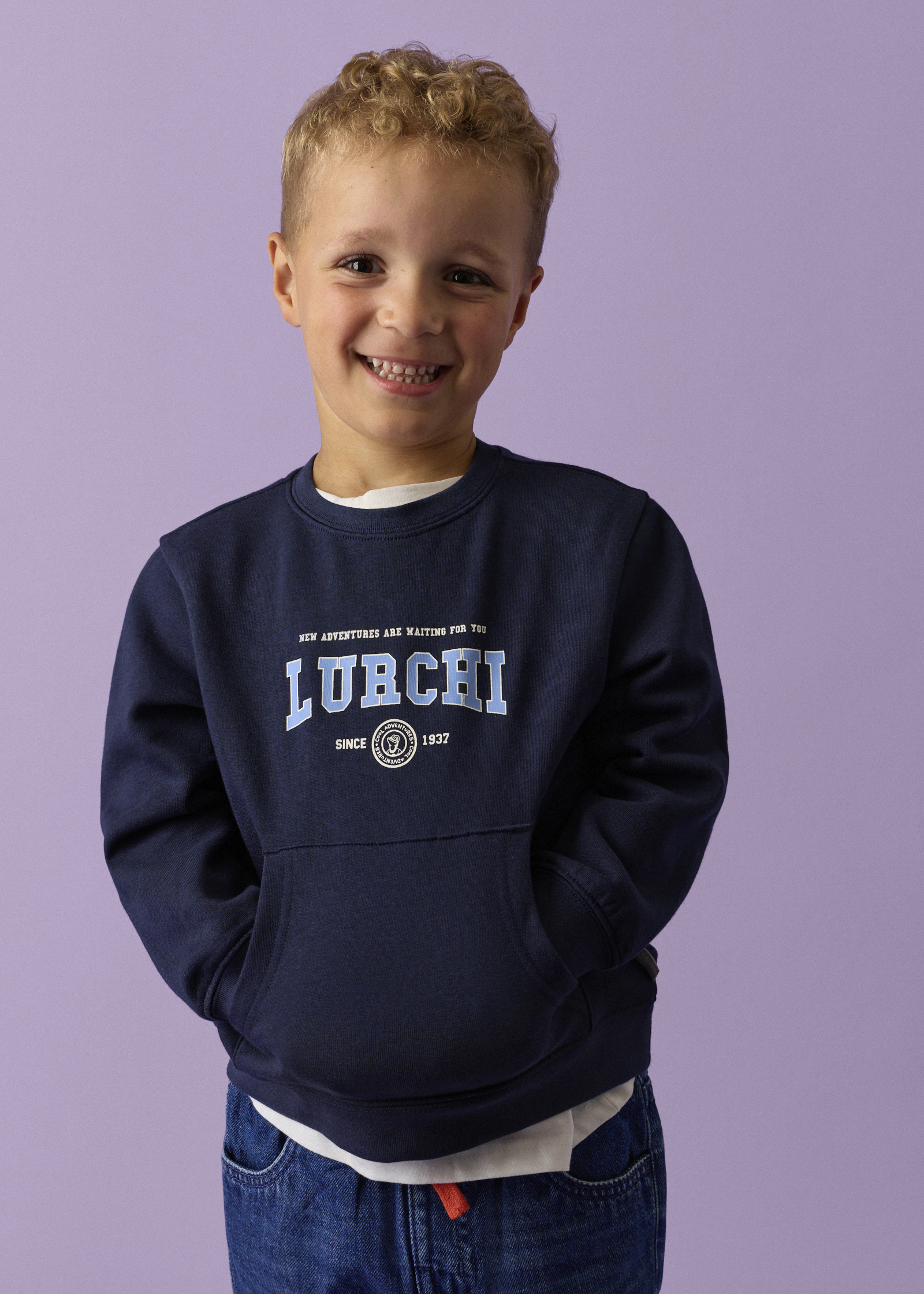 Dunkelblauer LURCHI-Sweatshirt mit Fronttasche und Jeans.