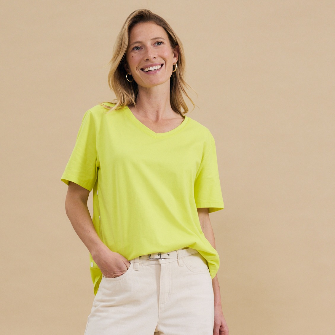 Leuchtend gelbes T-Shirt mit kurzen Ärmeln, kombiniert mit einer hellen Hose.