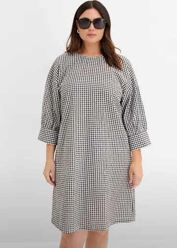 Locker geschnittenes, schwarz-weiß kariertes Kleid mit Dreiviertelärmeln.