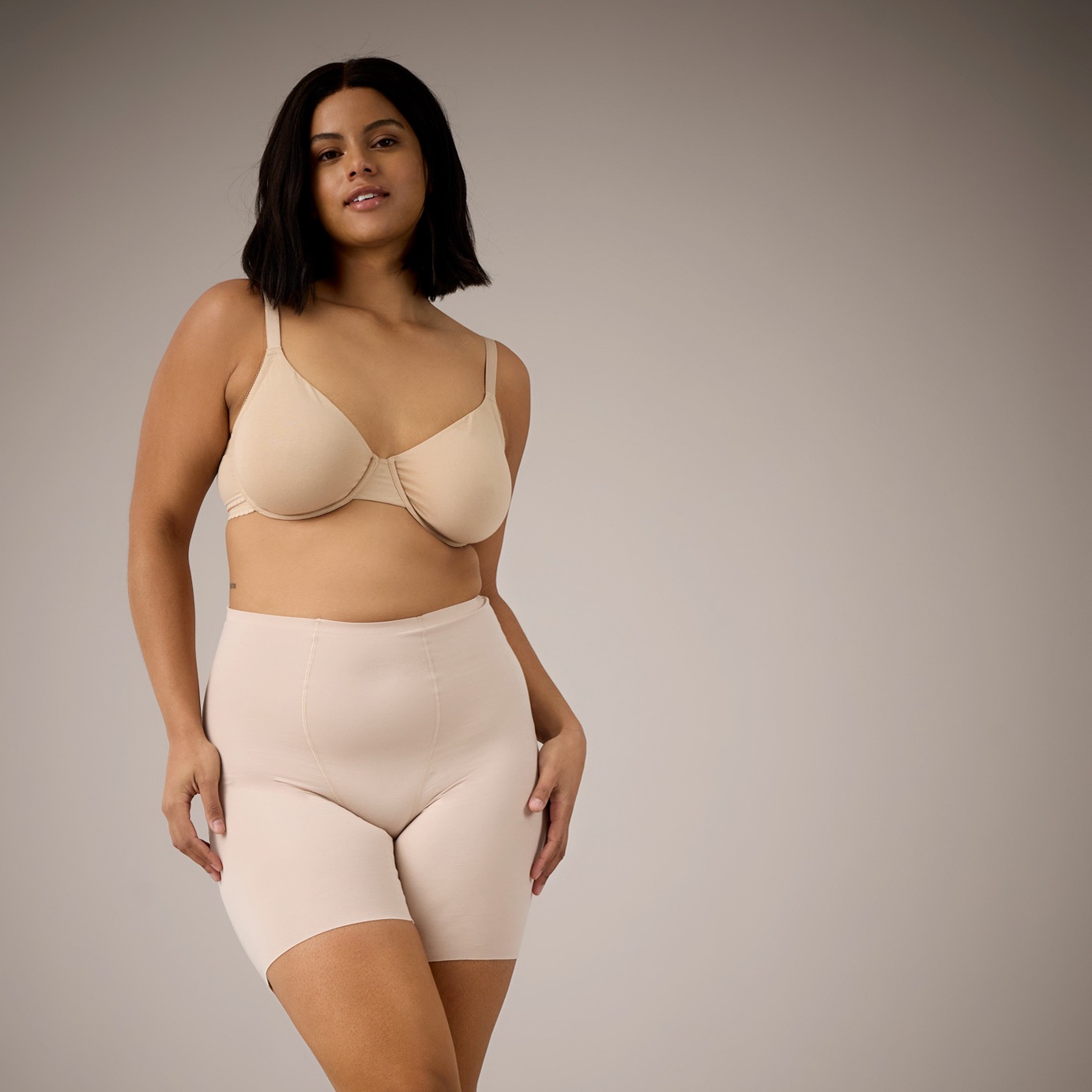 Beige Unterwäsche betont natürliche Schönheit. Elegante Silhouette auf cremefarbenem Sofa ruht entspannt.