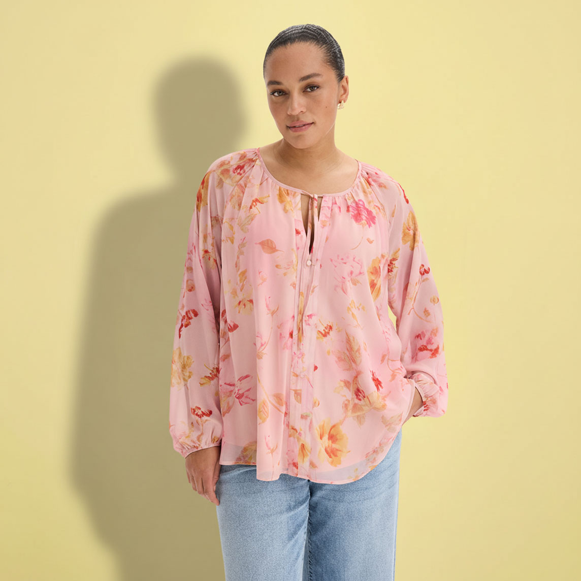 Eine rosa Bluse mit Blumenmuster und lockere Jeans.