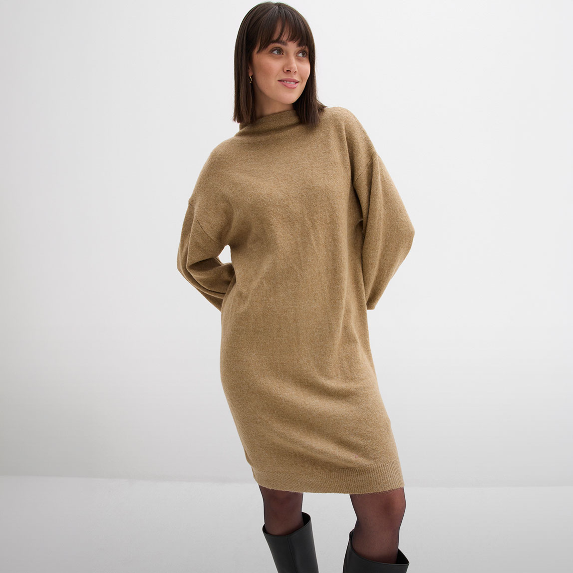 Gemütliches, kamelfarbenes Strickkleid, kombiniert mit schwarzer Strumpfhose und eleganten Stiefeln.