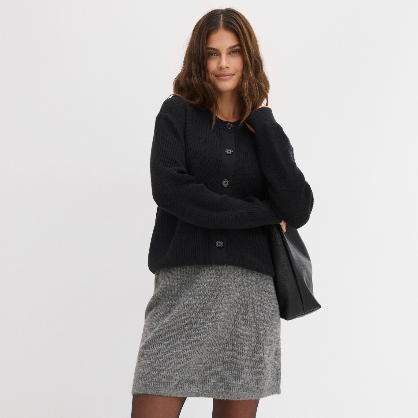 Elegante Kombination aus schwarzer Strickjacke und grauem Tweed-Rock für einen zeitlosen Business-Look.