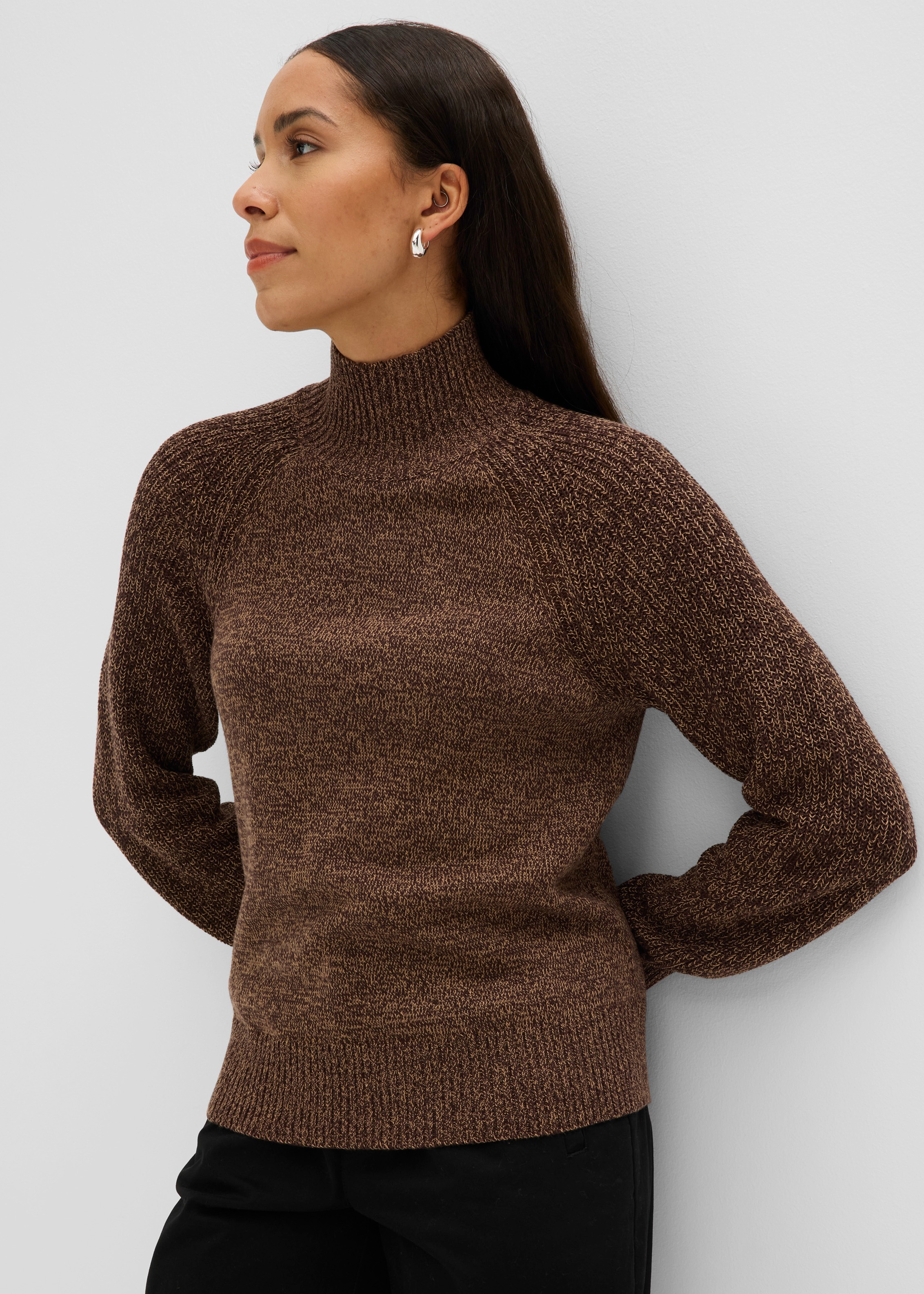 Brauner melierter Strickpullover mit Stehkragen und schwarzer Hose für einen eleganten Look.