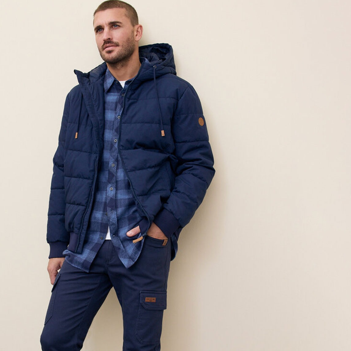 Marineblaue  Steppjacke, Jeans und blauem Karo-Hemd.