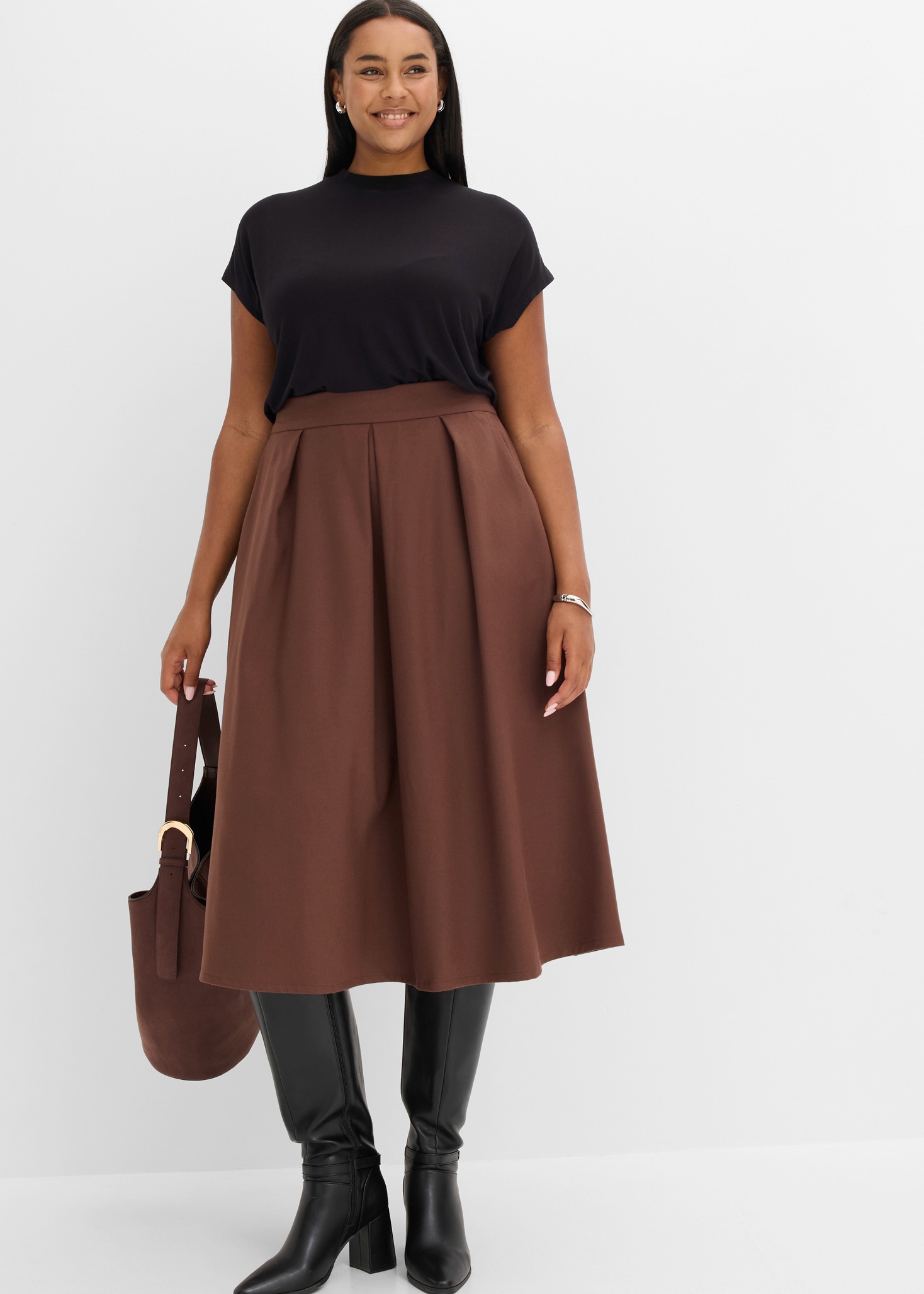 Eleganter Look mit schwarzem Top, braunem Midirock, schwarzen Stiefeln und passender Tasche.