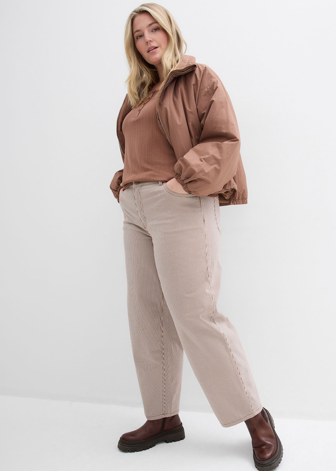 Braune Jacke und Top, beige Hose und dunkelbraune Schuhe.