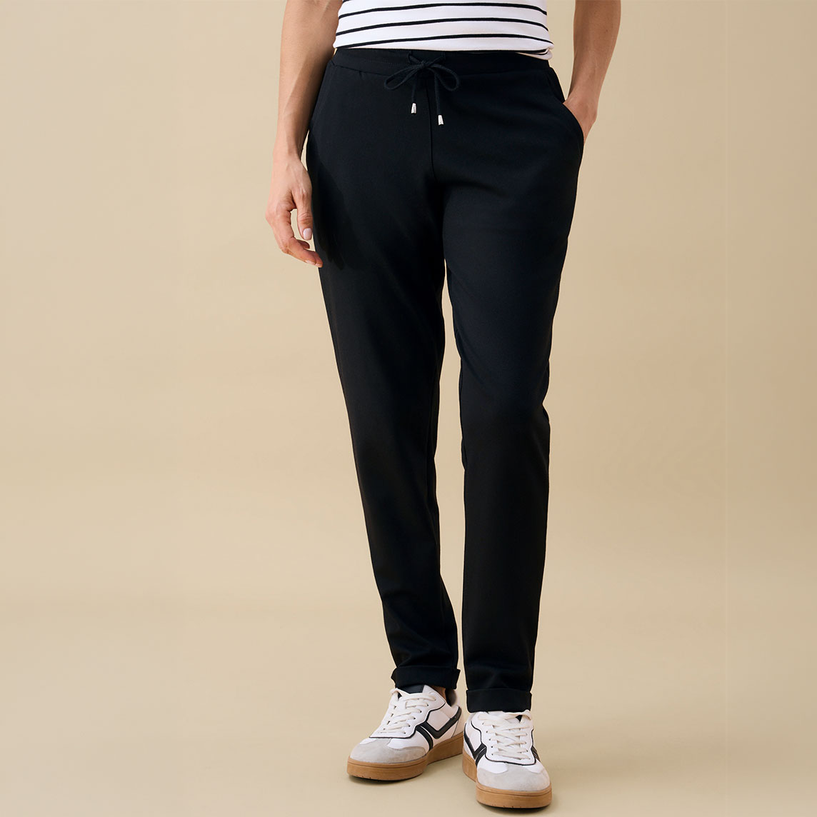 Schwarze Hose, gestreiftes Shirt und moderne Sneaker – ein komfortabler Casual-Look.