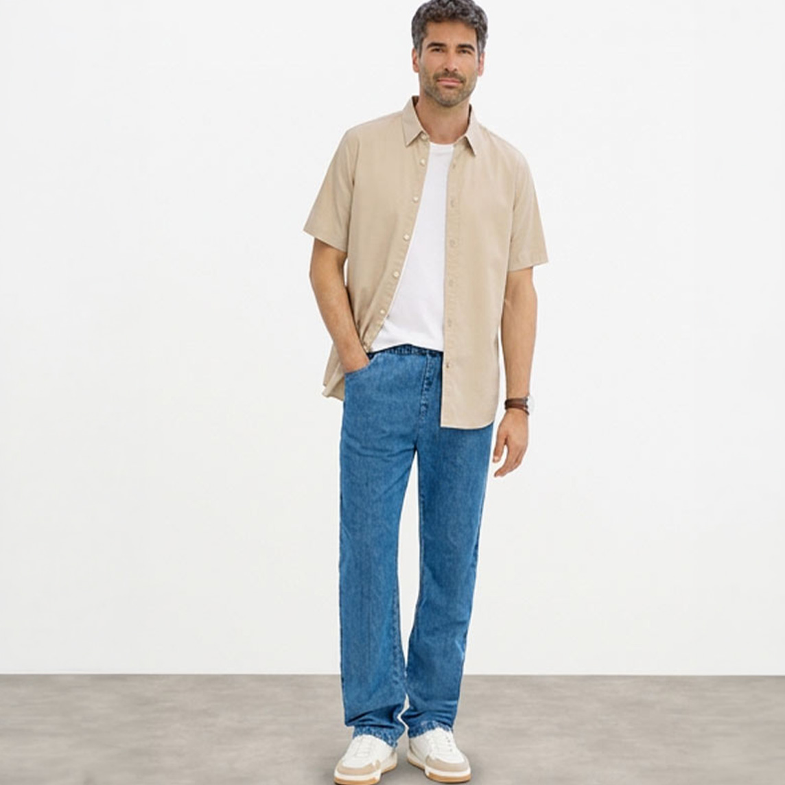 Beiges Kurzarmhemd, weißes T-Shirt, blaue Classic-Fit-Jeans und weiße Sneaker.