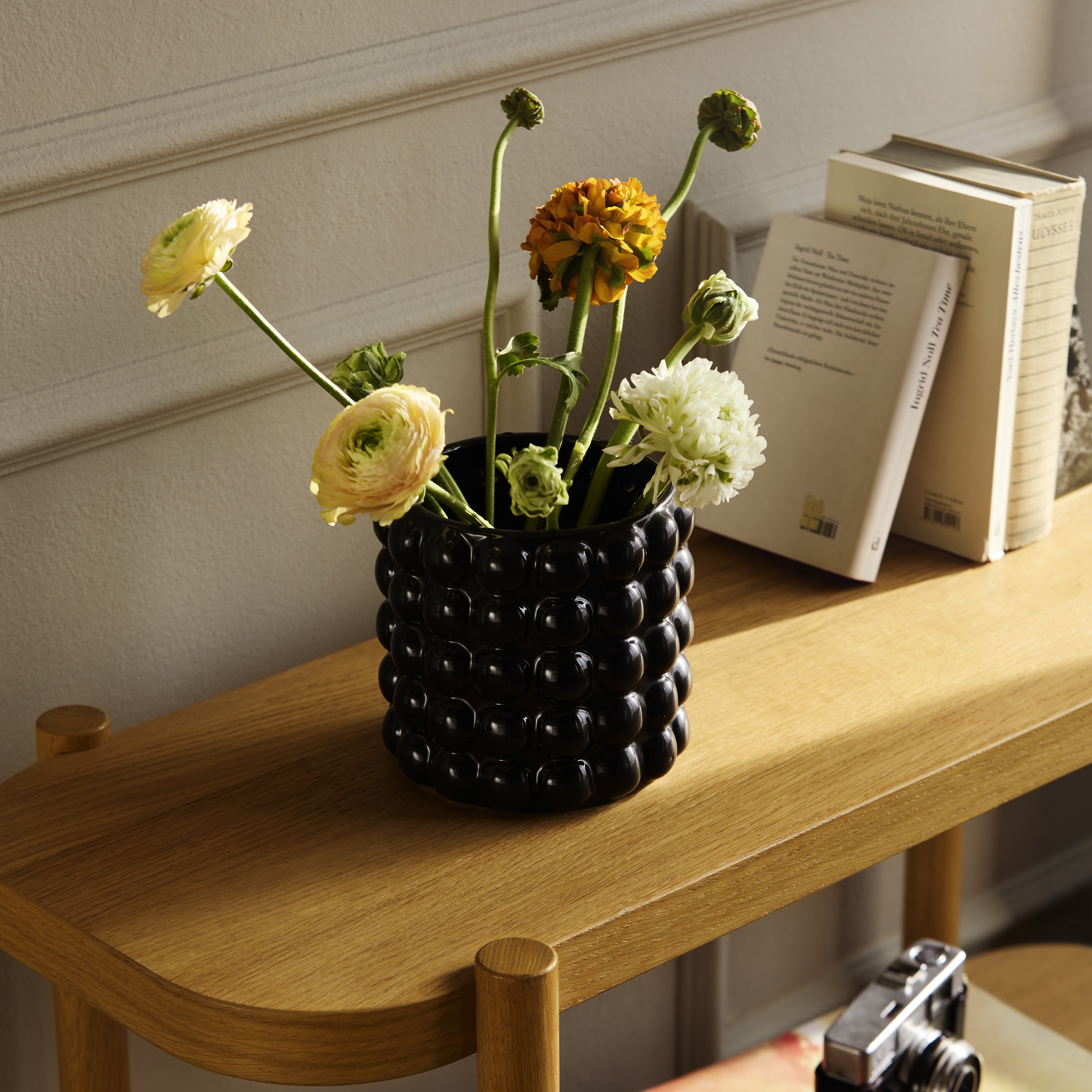 Auf dem Bild sind keine Kleidungsstücke zu sehen, nur Blumen in einer Vase auf einem Holztisch.