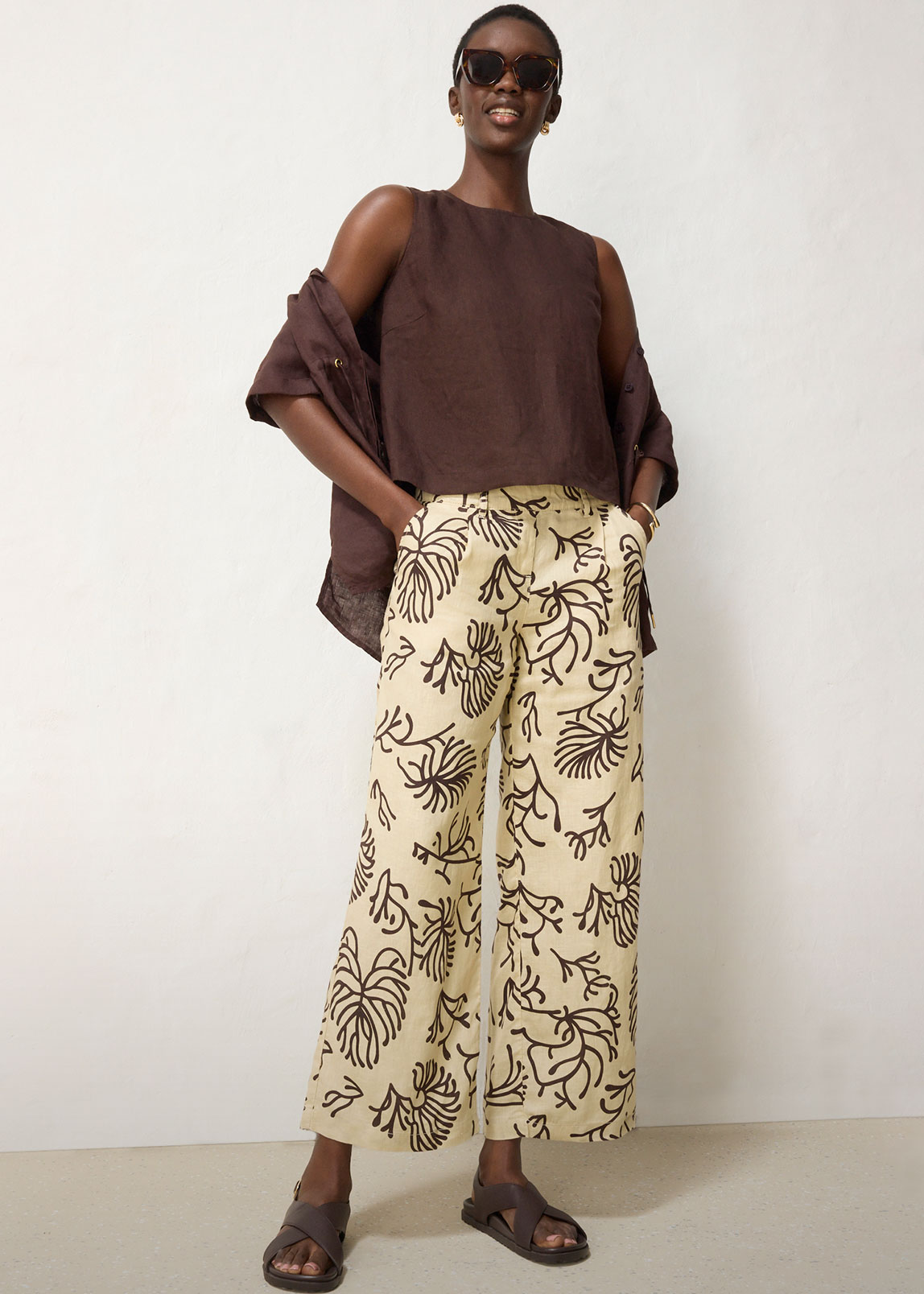 Dunkelbraunes Top, passendes Hemd, gemusterte Leinenhose und schicke Sandalen.