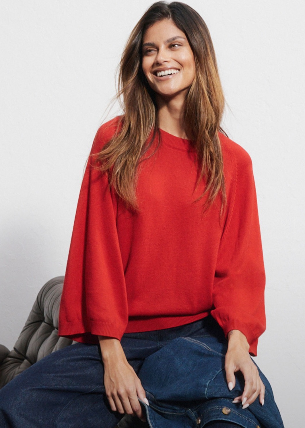 Roter Pullover mit weiten Ärmeln, dazu blaue Jeans und eine Jeansjacke.