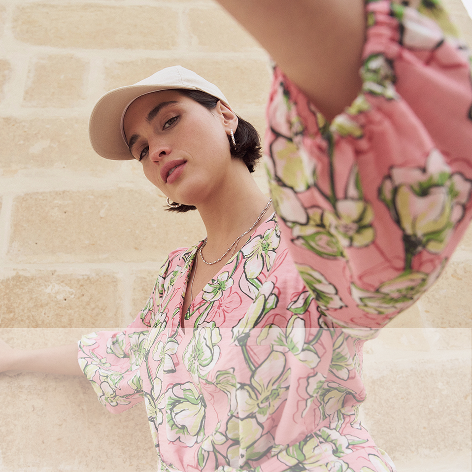 Farbenfrohe Bluse mit floralem Muster. Sommerlicher Hut in Beige. Elegante, feminine Sommermode.