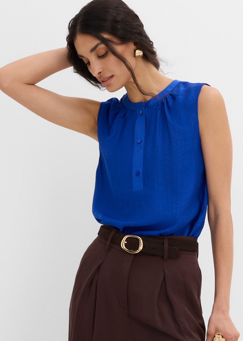Leuchtend blaues ärmelloses Top, perfekt kombiniert mit eleganter brauner Hose und Gürtel.