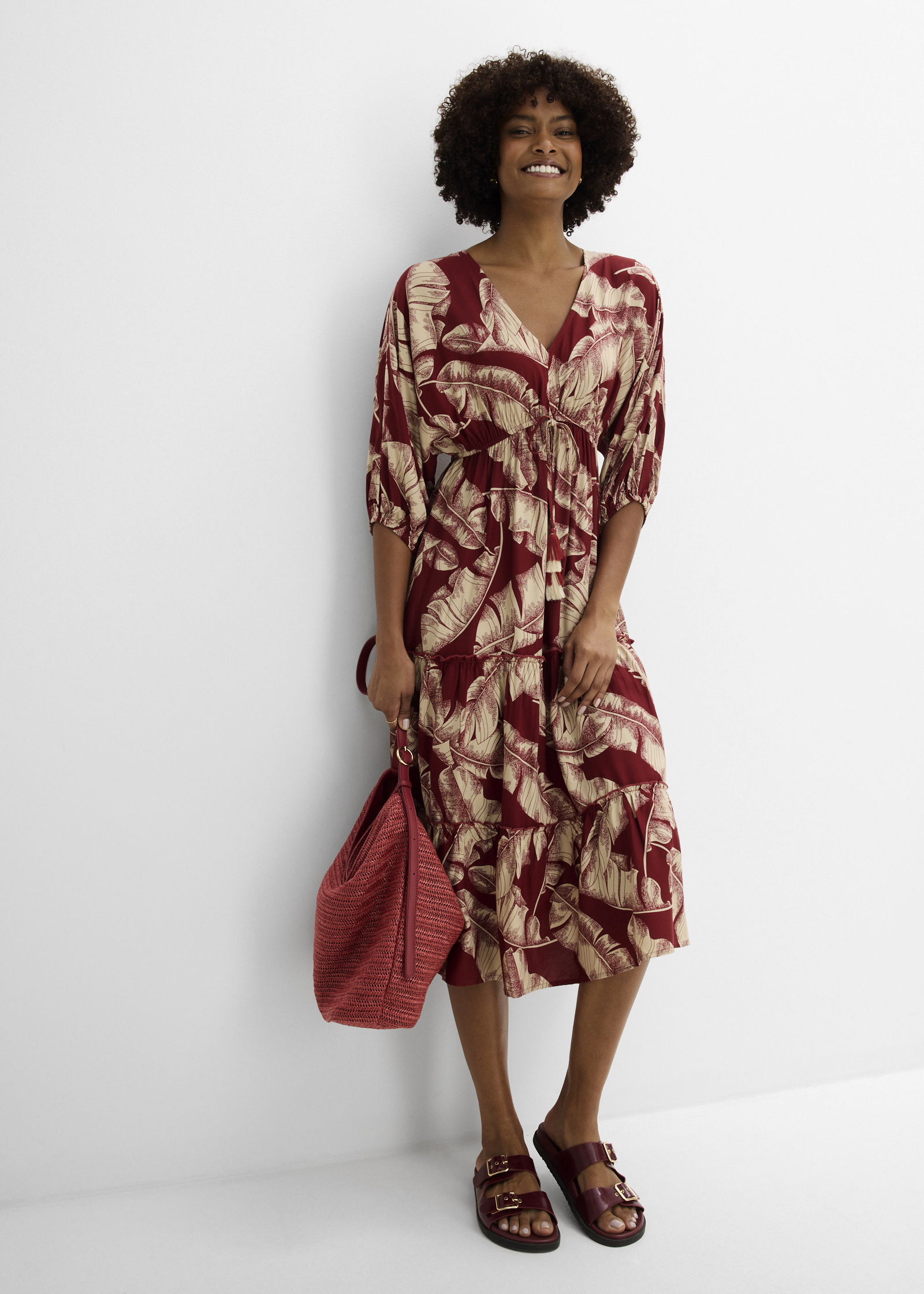 Luftiges Midikleid mit Blattmuster, dazu passende Tasche und rote Sandalen.