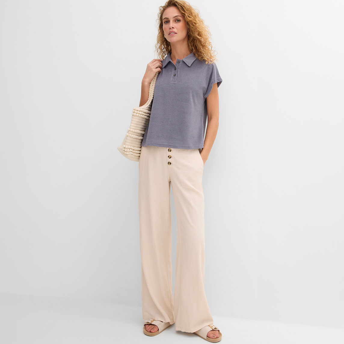 Elegante Frau trägt blaues lockeres T-Shirt und weite beige Hose im lässigen Stil.
